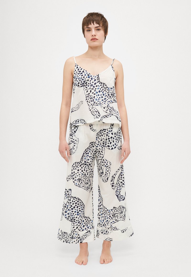 Loose-fitting, sleeveless pajama set in light fabric featuring a white background with large black and blue leopard print patterns.
