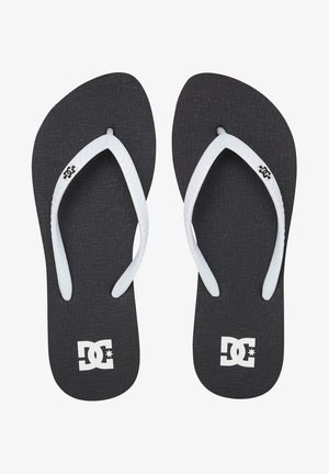 Chancletas negras con plantilla negra texturizada, correas de goma blanca y logo de DC en blanco en la suela. Diseño simple y plano.