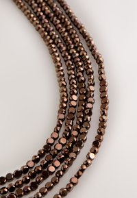 Brown faceted glass beads strung together, featuring a shiny finish with a smooth texture, arranged in multiple layers.