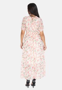Vestido maxi floral en tela ligera y translúcida. Presenta un patrón de rosas en tonos rosa y verde, cintura ceñida y un escote en forma de lágrima con lazo.