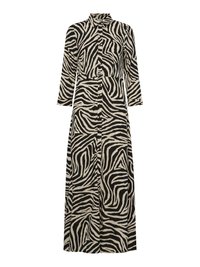 Vestido com padrão de zebra, mangas longas, colarinho, fecho frontal com botões e uma silhueta fluida nas cores preto e bege. Confeccionado em tecido leve.