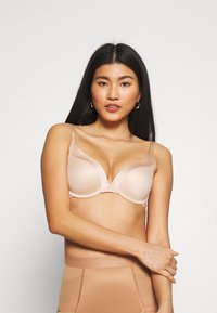 Trådløs nude bh med glatte formede kopper og justerbare stropper. Materialet er blødt med et sømløst design, der forbedrer komfort og pasform.