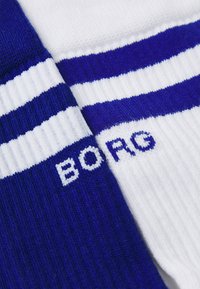 Blå og hvide sokker med ribbet tekstur, der har vandrette striber og et broderet "BORG" logo i blåt på den hvide sektion.