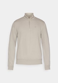 Μπεζ φούτερ με φερμουάρ μέχρι τη μέση, κατασκευασμένο από μαλακό ύφασμα, με ριμπ γιακά, μανσέτες και τελείωμα, με μικρό λογότυπο στο στήθος.