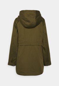 Veste à capuche vert olive, à coupe droite, en tissu texturé, avec des poignets à boutons-pression. Le design du dos présente une couture horizontale au niveau de la taille.