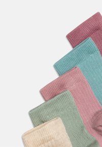 Bunte gerippte Socken in einem Farbverlauf: hellbeige, mintgrün, staubiges Rosa und türkis, die unterschiedliche Texturen und Bündchenhöhen präsentieren.