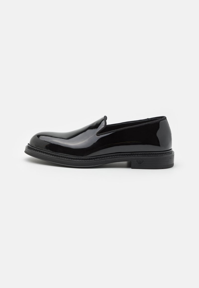 Schwarzer Lackleder-Slipper mit runder Zehenpartie, verfügt über eine strukturierte Sohle und dezentes Branding an der Ferse. Glatte Oberflächenstruktur.