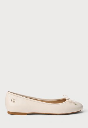 Beżowe skórzane baletki z zaokrąglonym czubkiem, detal w postaci kokardy z przodu oraz małym srebrnym emblematem na pięcie. Gładka tekstura, minimalistyczny design.