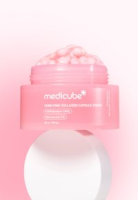 Lyserød krukke med PDRN Pink Collagen Capsule Cream, rund form, gennemsigtigt låg og synlige lyserøde kapsler indeni. Hvid cirkelbasen.