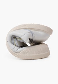 Zapato de cuero blanco con un diseño flexible, que cuenta con una suela beige texturizada y detalles de costura visibles. Usado y enrollado para mayor compactibilidad.