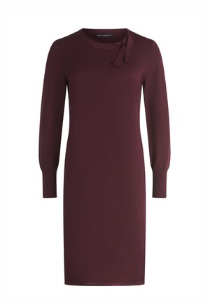 Bourgognefarvet kjole med rund halsudskæring, lange ærmer og sløjfedetalje ved kraven. Glat stof med en figursyet silhuet.