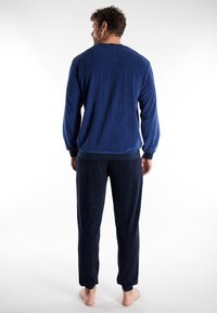 Conjunto de loungewear de polar azul marino que incluye un suéter acanalado y pantalones a juego con puños elásticos. Textura suave y ajuste relajado.