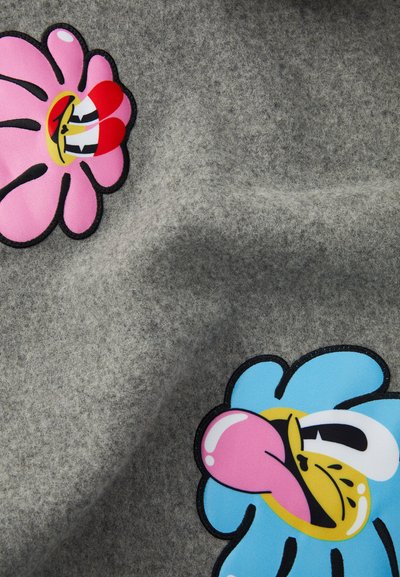Gråt stof med to tegneserieblomstermotiver, en pink og en blå, med kraftige konturer og legende ansigtsudtryk.