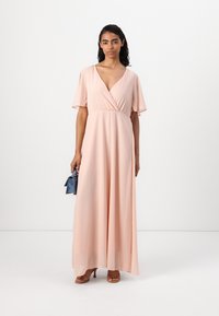 Rochie maxi roz blush cu decolteu în V, mâneci scurte fluturătoare și talie empire. Materialul neted se așază elegant până la podea.