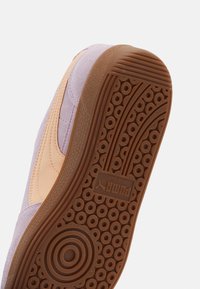 Sneaker sole featuring a textured rubber bottom with circular patterns, light purple suede upper, and tan leather accents.