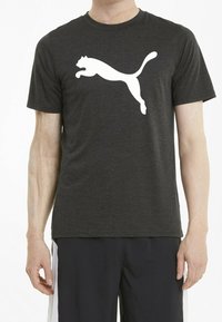 Svart prestations t-shirt gjord av ventilerande tyg som har en stor vit Puma-logotyp över bröstet, med rund hals och korta ärmar.