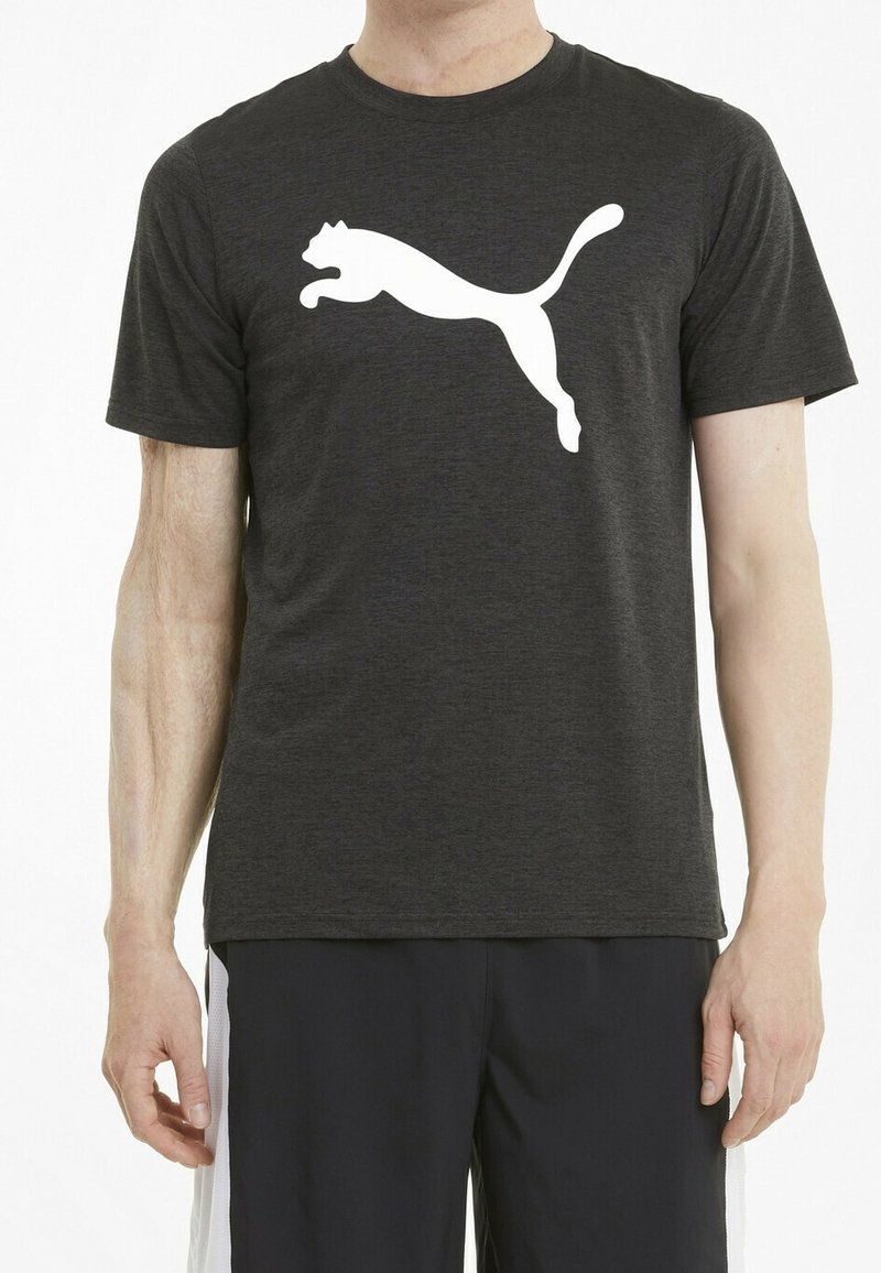 Svart prestations t-shirt gjord av ventilerande tyg som har en stor vit Puma-logotyp över bröstet, med rund hals och korta ärmar.
