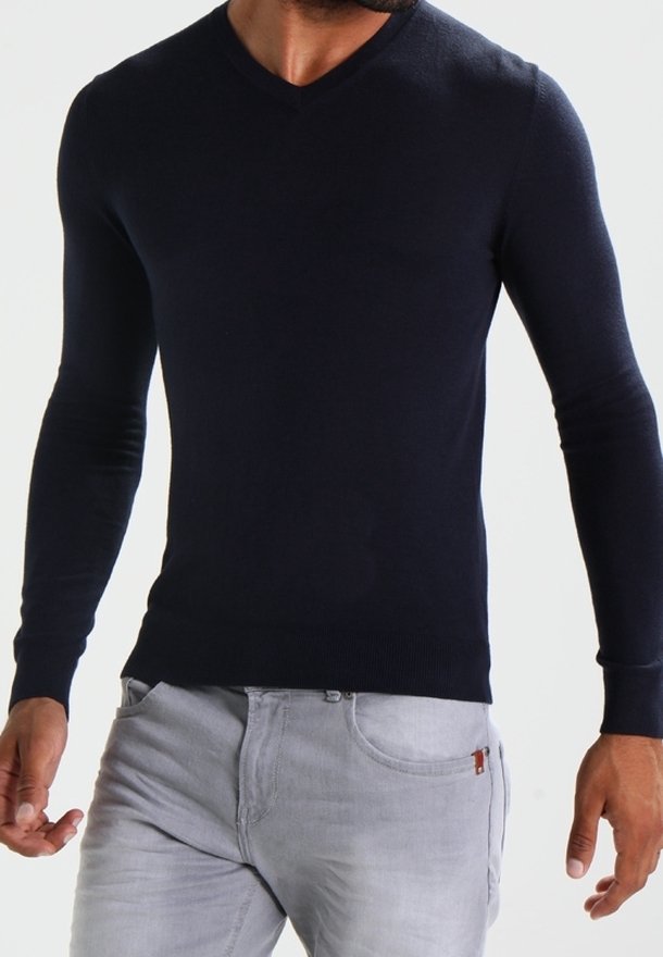 Mörkblå, långärmad V-ringad tröja gjord av mjukt material, med ribbade mudd och nederkant, tillsammans med ljusgrå jeans.