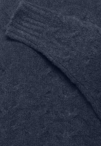 Pull en maille bleu foncé avec des poignets côtelés et un motif texturé sur le corps. Tissu doux et pelucheux au look confortable.