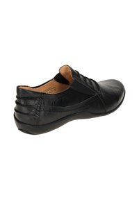Black leather shoe with a low profile, textured finish, elastic side accents, and a rounded toe. Includes stitched detailing on the sides.