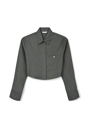 Camicia a maniche lunghe tagliata in tessuto di un verde scuro. Presenta un colletto a punta, tasca frontale con dettaglio di bottone e dettagli di cucitura visibili.