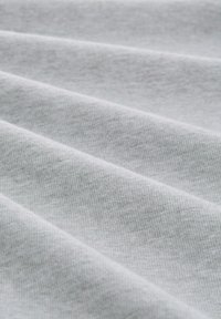 Tejido de color gris claro, texturizado con suaves nervaduras, que presenta pliegues y arrugas que crean una superficie dinámica. Coloración uniforme a lo largo de toda la tela.