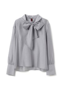 Blusa grigia chiara con colletto a fiocco, maniche lunghe a sbuffo e tessuto liscio e lucido. Presenta una linea dritta e un orlo leggermente arrotondato.