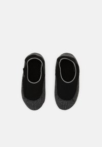 Calzini pantofole grigi con parte superiore nera e texture, e bordi grigi. Tessuto morbido e design a taglio basso, adatti per uso interno.