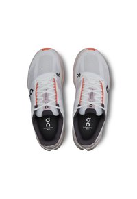 Weiße Laufschuhe mit Netzeinsatz, orangen Akzenten und schwarzem Logo. Sie haben flache Schnürsenkel und gepolsterte Einlegesohlen mit Branding auf der Zunge.