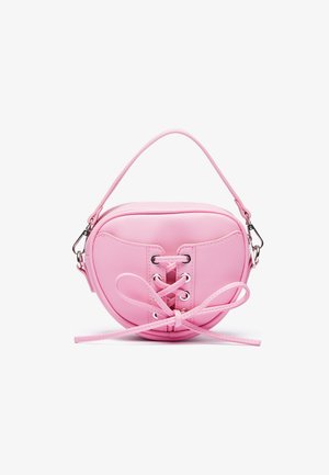 Pink faux leather handbag with a circular shape, featuring lace-up design with metallic eyelets and a bow detail. Includes a short handle.