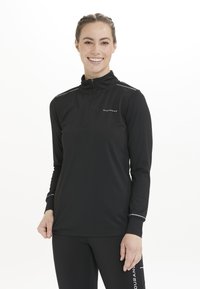 Sort langærmet atletisk top med halv lynlås-cola, refleksdetaljer på skuldrene, lavet af fugttransporterende materiale til aktiv brug.