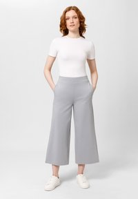 Lichtgrijze wijde broek met een zachte textuur, met een hoge tailleband en zijzakken, gecombineerd met een aansluiten wit T-shirt met korte mouwen.