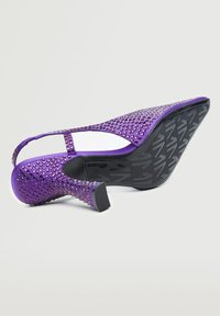 Chaussure pour femme à talon haut violette avec bride arrière, ornements carrés et semelle noire texturée sur fond blanc.