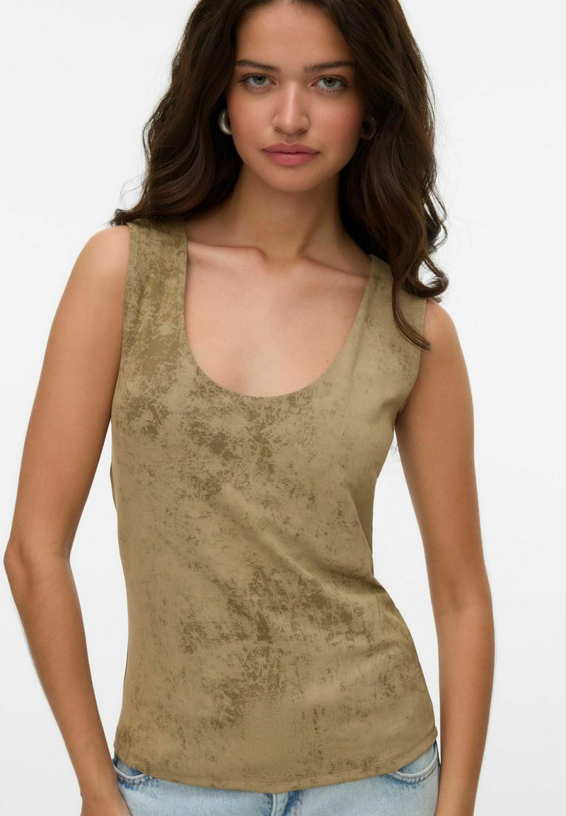 Top khaki senza maniche con scollatura tonda, texture liscia e delicato motivo irregolare. Abbinato a jeans in denim azzurri chiari.