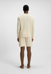 Beige wafelgebreide top met lange mouwen en bijpassende shorts, met een ontspannen pasvorm en zachte textuur, gezien vanuit de achterkant.