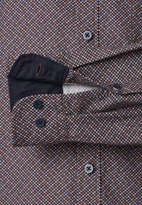 Braun-blau gemustertes Hemd mit schwarzen Knöpfen, versehen mit einem kontrastierenden, strukturierten Kragen und Manschetten. Die Knöpfe sind vorne gleichmäßig angeordnet.