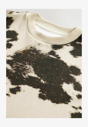 Sudadera de algodón con una base beige y un patrón abstracto de manchas de vaca en blanco y negro como contraste, acabada con un cuello redondo de canalé.