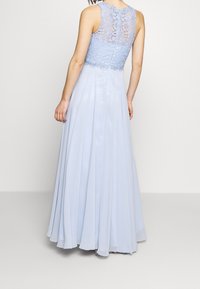 Světle modré šaty s krajkovým živůtkem s květinovými vzory, kulatým výstřihem a splývavou plisovanou sukní. Zapínání na zip na zadní straně.