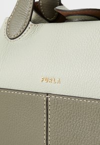Teksturirana kožna torba u svijetlozelenoj i prigušenoj maslinastoj boji, s zlatnim logotipom i kontrastnim šavovima na spoju.