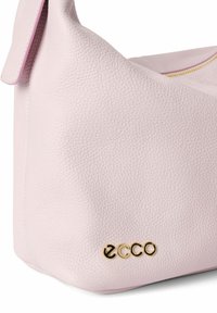 Mjuk rosa läderhandväska med en pebblade struktur, med en guldfärgad logotyp och enkel design. Inkluderar en sidoflik för stängning.