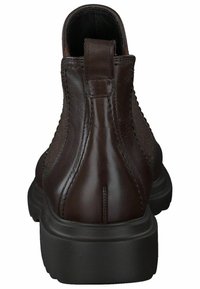 Bota de tobillo de cuero marrón con superficie suave, paneles laterales elásticos y una notable pestaña trasera para tirar. Suela de goma negra gruesa.