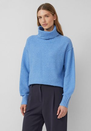Hellblaue Rollkragenpullover aus strukturiertem Stoff. Verfügt über einen leicht verkürzten Schnitt und gerippte Bündchen, kombiniert mit dunklen Hosen.