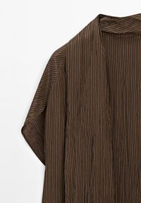 Brun kimono med lodrette sorte striber. Letvægtsstof, åben frontdesign og brede ærmer. Tekstureret udseende med subtil glans.