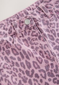 Denim con stampa leopardata rosa con cuciture visibili, un bottone in metallo e una tasca frontale. Il tessuto presenta una sottile trama a coste.