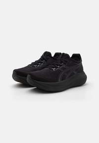 Black athletic shoes made of textured fabric, featuring a sleek design, rounded toe, and thick rubber sole with subtle branding accents.