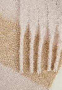 Zachte, beige en lichtroze wollen sjaal met een fluffy textuur en franjeranden, liggend plat.