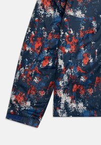 Giacca con motivo astratto nei colori blu navy, rosso e bianco, realizzata in un tessuto testurizzato e con polsini a contrasto. Design a maniche lunghe.