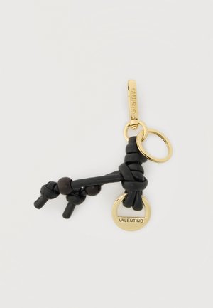 Mustat solmittu nahkainen avainnauha, jossa on kullanväriset renkaat, joista yhteen on kaiverrettu "Valentino", yksinkertaisen vaalean taustan edessä.