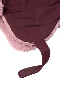 Bordeaux fleece deken met een roze fluffy voering. Beschikt over een zachte textuur, een klittenbandsluiting voor het vastmaken en een reliëf logo detail.