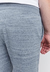 Grijze katoenen joggers met een gestructureerde afwerking en elastische tailleband. Voorzien van een achterzak aan de rechterkant.